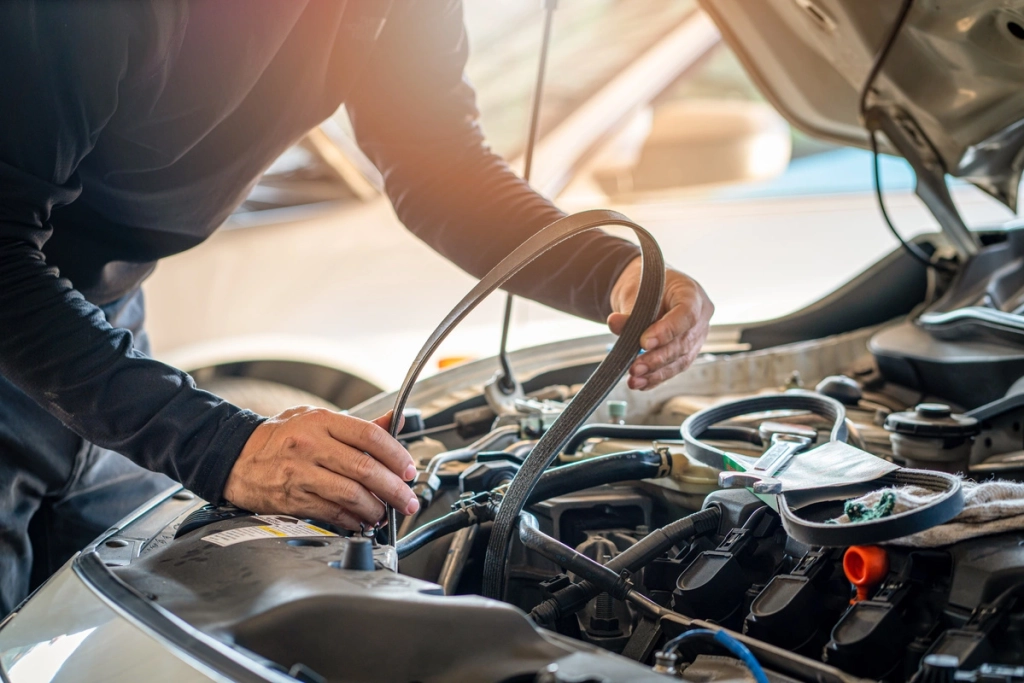 Mécanicien effectuant le remplacement d'une courroie de distribution dans le moteur d'une voiture.